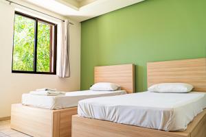 two beds in a room with green walls at Maui Poolside Studios in Laganas