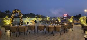 a group of tables and chairs on a patio at night at Hotel Central Palace in Dehradun