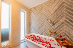 a bathroom with a white tub with red flowers on it at Casa Mandala by ELIVAAS in Candolim