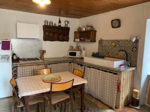 a kitchen with a table with chairs and a refrigerator at Maisonnette ardéchoise au centre du village in Nozières