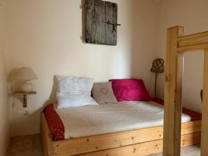a bedroom with a wooden bed with pink and white pillows at Maisonnette ardéchoise au centre du village in Nozières