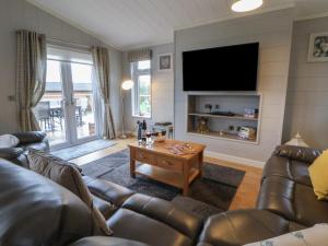 a living room with leather furniture and a flat screen tv at Holly Lodge in Holywell