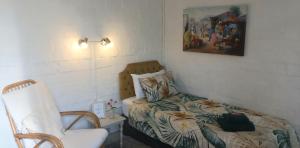 a small bedroom with a bed and a chair at 19 on Robyn in Durbanville