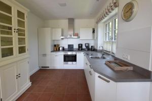 a kitchen with white cabinets and a clock on the wall at Ferienhaus Helen in Morsum