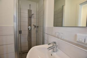 a bathroom with a sink and a shower with a mirror at Ferienhaus Alte Dorfstraße 20 in Tinnum +16 photos