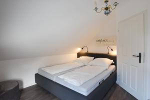 a bed with white sheets and pillows in a room at Ferienhaus Erika in Tinnum
