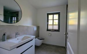 ein weißes Badezimmer mit Waschbecken und Spiegel in der Unterkunft Ferienhaus Calluna Stilvolle Doppelhaushälfte in der Lüneburger Heide, Hunde willkommen in Winsen