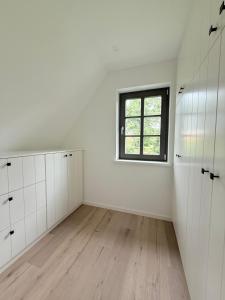 ein leerer Raum mit weißen Schränken und einem Fenster in der Unterkunft Ferienhaus Calluna Stilvolle Doppelhaushälfte in der Lüneburger Heide, Hunde willkommen in Winsen