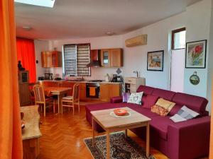a living room with a purple couch and a kitchen at Villa Jasmin in Aheloy