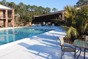 彭薩科拉的住宿－At Home Inn - Pensacola，一座带椅子和桌子的游泳池位于大楼旁