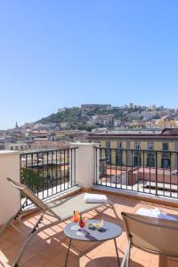 a balcony with chairs and tables on a roof at Hotel Piazza Bellini & Apartments in Naples