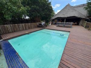 a large swimming pool on a wooden deck with a bench at Roaring Sky Base Camp in Cullinan