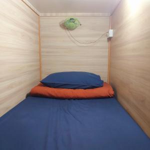 a small bed in a room with a wooden wall at BRICKS Backpackers Sleepbox in Tanah Rata