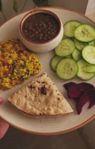 a plate of food with guacamole and beans and a tortilla at Hotel Casa Square in Indore