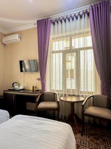 a hotel room with a bed and a desk and a window at Gold Camel Registan in Samarkand