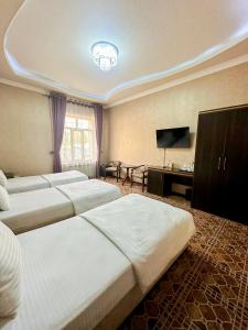 a hotel room with three beds and a flat screen tv at Gold Camel Registan in Samarkand