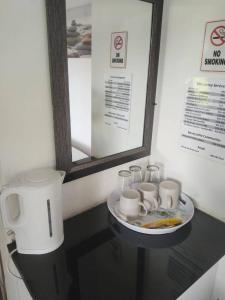 a table with a plate of cups and a coffee pot at Memories Vaaldam in Denysville