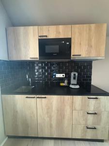 a kitchen with wooden cabinets and a black microwave at Minimalist apartment - Lier center in Lier +6 photos