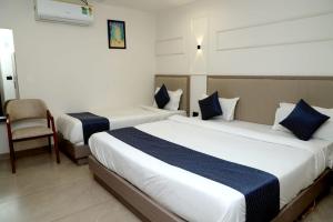 ein Hotelzimmer mit zwei Betten und einem Stuhl in der Unterkunft hotel the perfect in Ahmedabad
