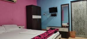 a bedroom with a bed and a tv on the wall at Hotel Mainak Mandarmoni in Mandarmoni