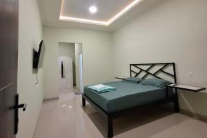 a bedroom with a bed in a white room at Sultan Guest House in Palu
