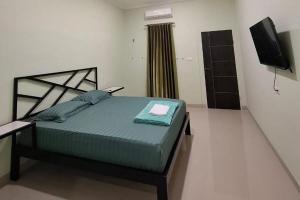 a bedroom with a bed and a television in it at Sultan Guest House in Palu