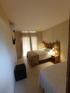 a hotel room with two beds and a suitcase at Recanto dos Coraiss in Marau