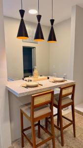 a kitchen with a table with chairs and pendant lights at Studio de Hóspedes - 150m da Praia in Rio de Janeiro