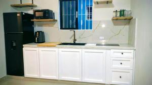 a kitchen with white cabinets and a black refrigerator at Solano Apartamentos in Boca Chica
