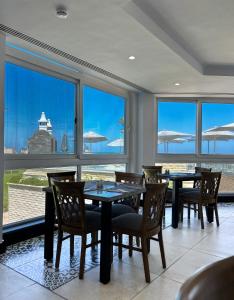 a dining room with tables and chairs and large windows at Borg El Arab Beach Resort in Dawwār ‘Abd al Qādir Qāsim