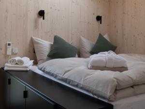 a large white bed with towels on top of it at Hapfn Tiny Houses mit Hot Tub in Eibiswald +8 photos