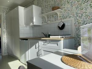 Eine Küche mit weißen Schränken und geblümter Tapete in der Unterkunft Vita huset at Stora Le in Ed + 22 Fotos