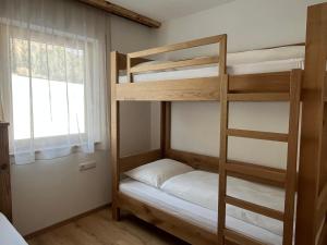 a bunk bed room with two bunk beds and a window at Mountain River Apartment in Chienes
