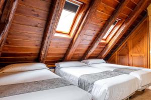three beds in a room with wooden walls at Hostal Nau Pradets in Vielha