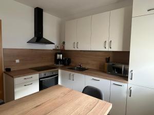 a kitchen with white cabinets and a wooden table at Mountain River Apartment in Chienes