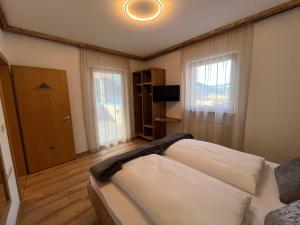 a bedroom with a bed and a television and windows at Mountain River Apartment in Chienes