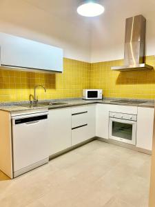 a kitchen with white appliances and yellow tiles at Loft Manuel Arellano in Seville