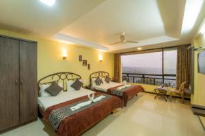 two beds in a room with a balcony at Hotel Indira Nature Valley Mahabaleshwar in Mahabaleshwar