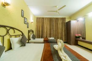 a hotel room with a bed and a bed and a window at Hotel Indira Nature Valley Mahabaleshwar in Mahabaleshwar +19 photos