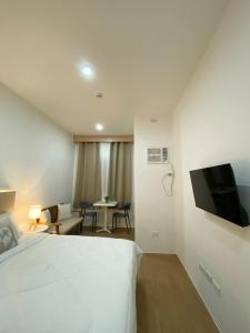 a bedroom with a white bed and a flat screen tv at The Studio Suites in Maribago