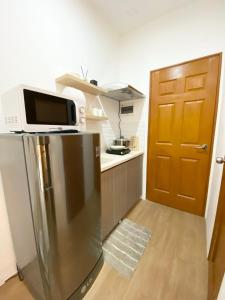 a kitchen with a microwave on top of a refrigerator at The Studio Suites in Maribago