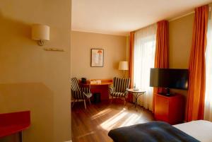 a hotel room with a bed and a desk with chairs at Hotel Ambiente in Dortmund