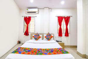 a bedroom with a large bed with red curtains at FabHotel Vhyom Sky Palace in Kolkata