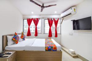 a bedroom with a bed with red curtains and a flat screen tv at FabHotel Vhyom Sky Palace in Kolkata +22 photos