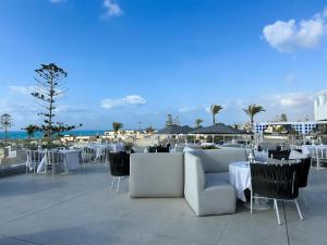 a restaurant with white tables and chairs and the ocean at Borg El Arab Beach Resort in Dawwār ‘Abd al Qādir Qāsim