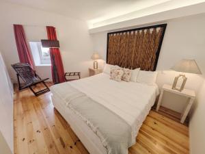 a bedroom with a large white bed with a window at Casa da Delonga in Nordeste