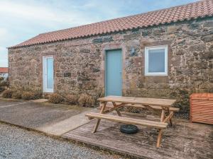 a wooden picnic table in front of a stone building at Casa da Delonga in Nordeste