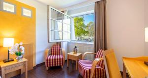 a hotel room with two chairs and a window at PLAZA INN Schmöker-Hof in Norderstedt +91 photos