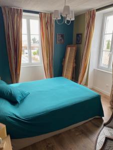 a blue bed in a room with windows at L'Olivier in Charron