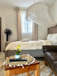a bedroom with a bed and a table with a couch at Rustic studio milimani in Kisumu